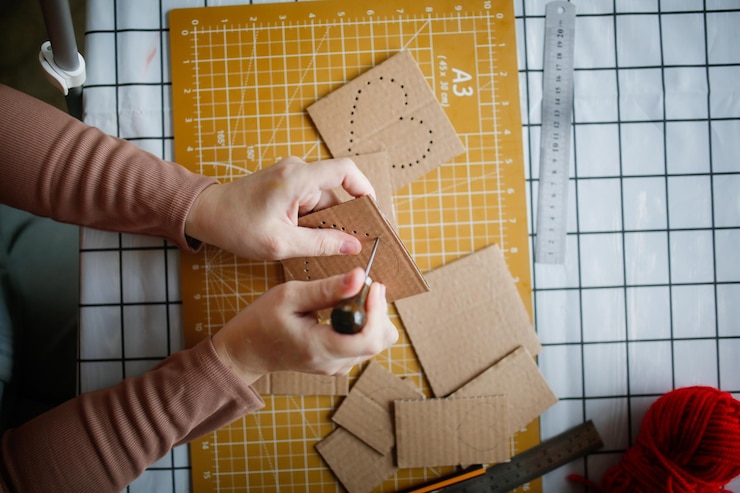 Foto mãos com iscas perfuram artesanato de papelão a partir de papelão