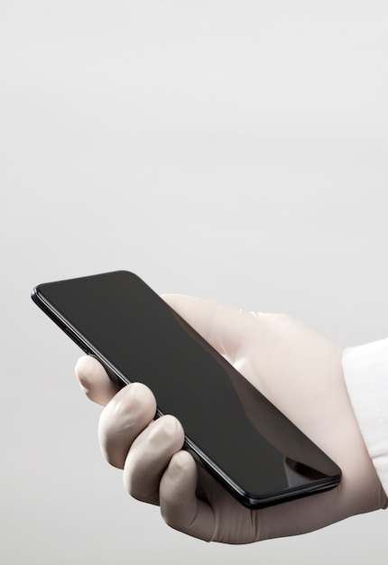 Mãos com luvas e telefone com tela cinza