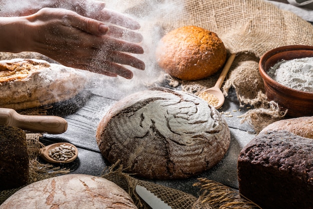 Mãos com pão na mesa de madeira escura