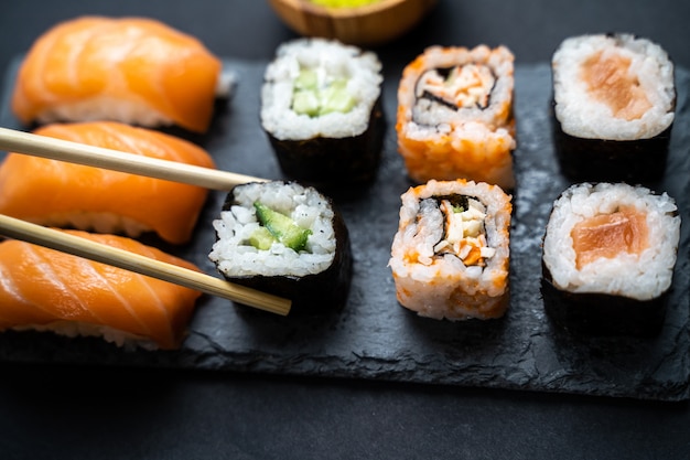 Mãos com paus segurando um sushi maki