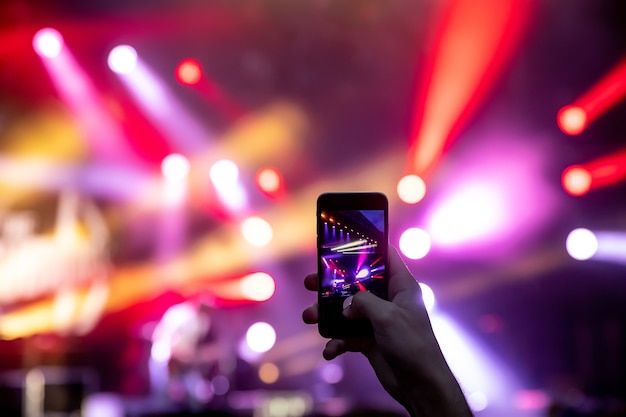 Mãos com um smartphone gravam festival de música ao vivo, concerto ao vivo