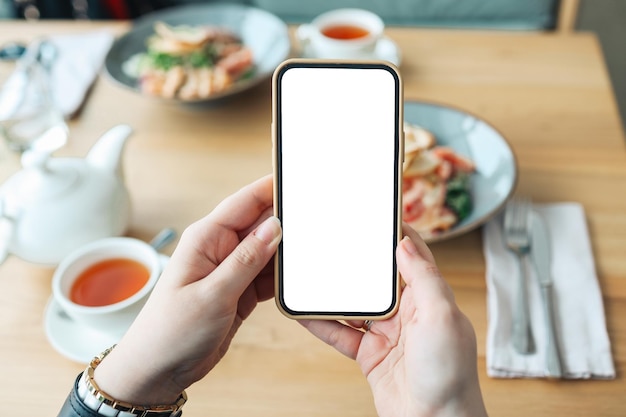 Mãos com uma tela de telefone isolada no fundo da comida em um café Lugar para o seu menu de revisão