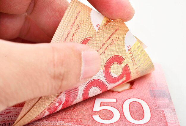 Mãos contando notas de 50 dólares canadenses