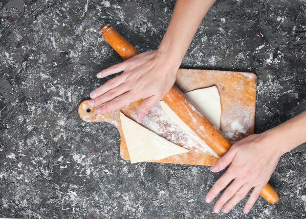 Mãos continuem rolando o pino e rolem a massa na mesa de concreto cinza