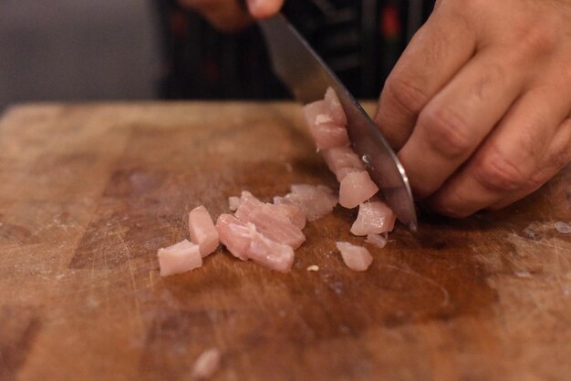 Mãos cortadas cortando peixe na tábua de cortar na cozinha