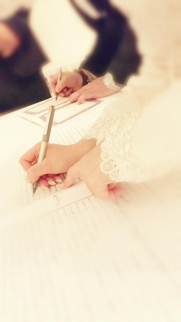 Foto mãos cortadas da noiva e do noivo escrevendo em livros