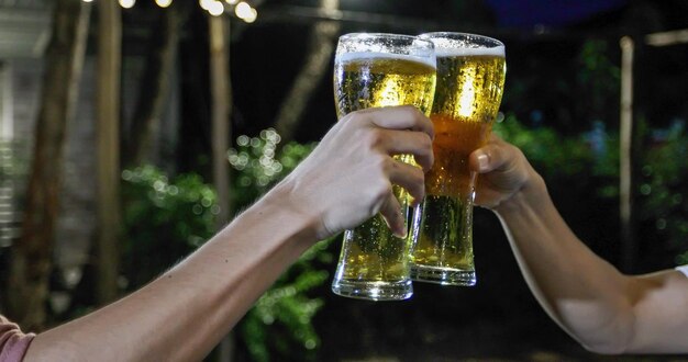 Foto mãos cortadas de amigos brindando com copos de cerveja.