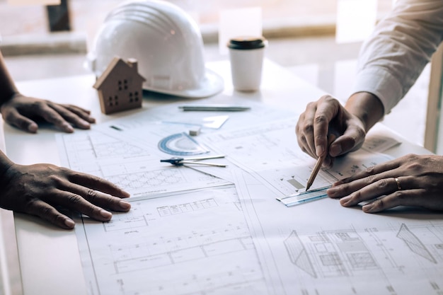 Mãos cortadas de arquitetos do sexo masculino desenhando planos na mesa