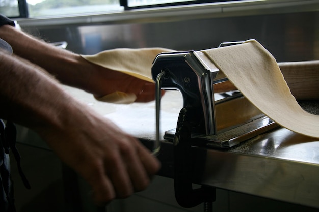 Mãos cortadas de chef preparando macarrão em cozinha comercial