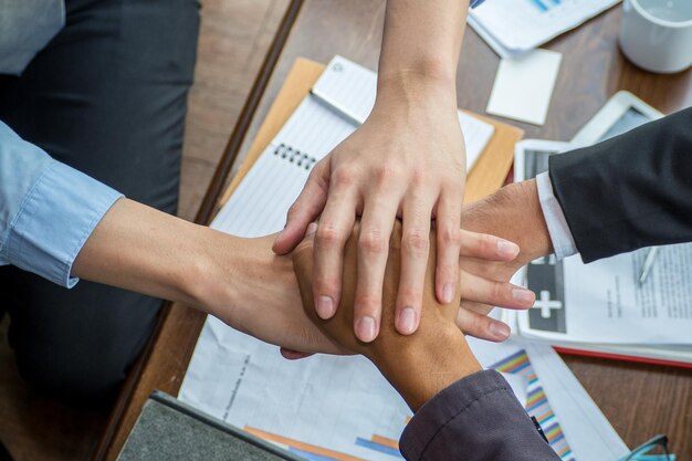 Mãos cortadas de colegas de trabalho empilhando mãos no escritório.