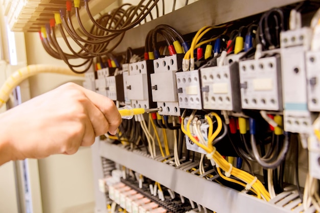 Mãos cortadas de eletricista reparando equipamentos elétricos