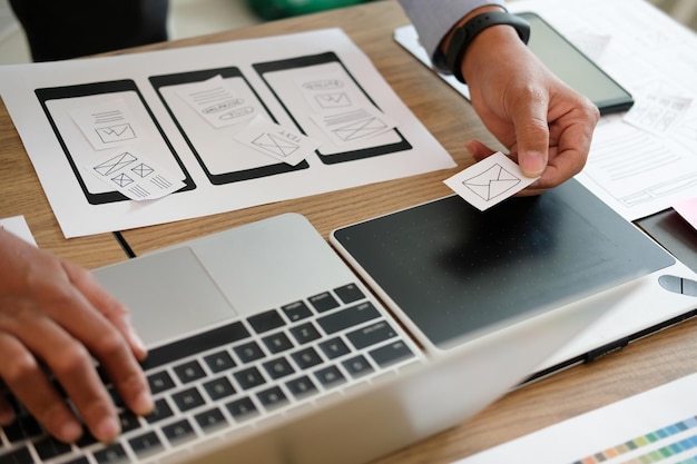 Foto mãos cortadas de empresário segurando papel enquanto usa laptop na mesa