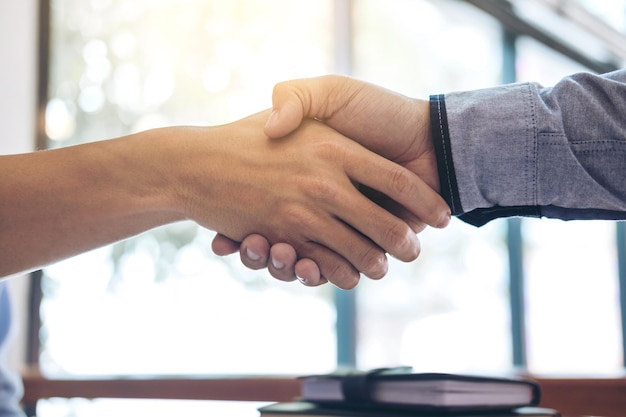 Foto mãos cortadas de empresários a apertar a mão no escritório.