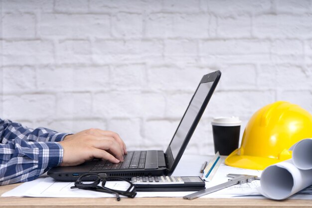 Mãos cortadas de engenheiro usando laptop na mesa