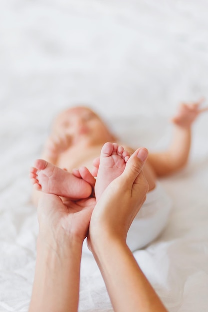Mãos cortadas de mãe segurando pés de bebê