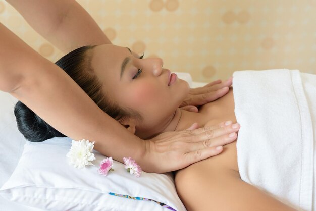 Mãos cortadas de massagista dando massagem a uma jovem mulher relaxando no spa