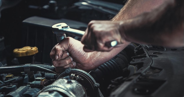 Mãos cortadas de mecânico reparando motor de carro