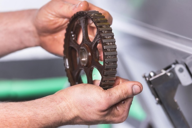 Foto mãos cortadas de mecânico segurando equipamento sujo em uma oficina de reparação de automóveis