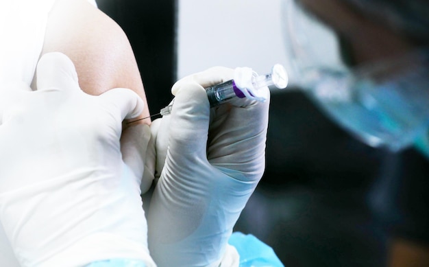 Mãos cortadas de médico injetando paciente