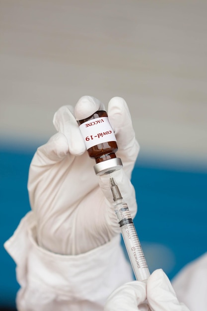 Mãos cortadas de médico segurando frasco e seringa
