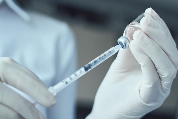 Mãos cortadas de médico segurando seringa e frasco