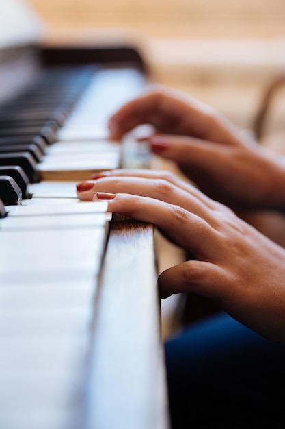 Mãos cortadas de mulher a tocar piano.