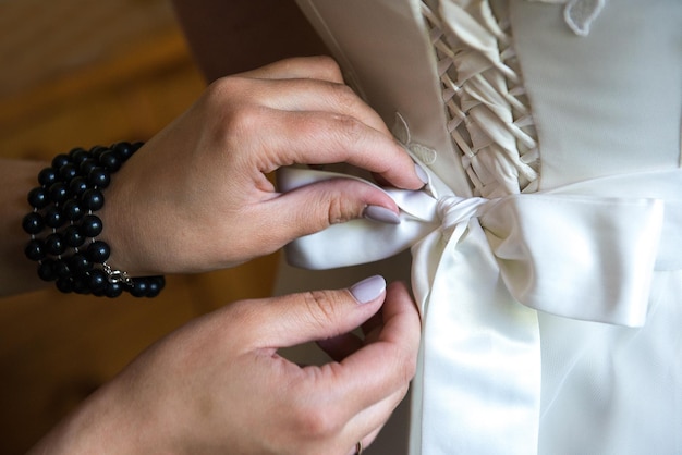 Foto mãos cortadas de mulher ajudando a noiva a se vestir