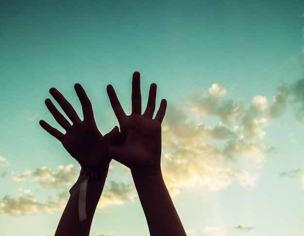 Foto mãos cortadas de mulher contra o céu durante o pôr-do-sol