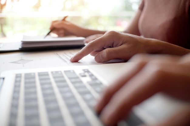 Foto mãos cortadas de mulher de negócios usando laptop enquanto discutia com um homem de negócios na mesa no escritório