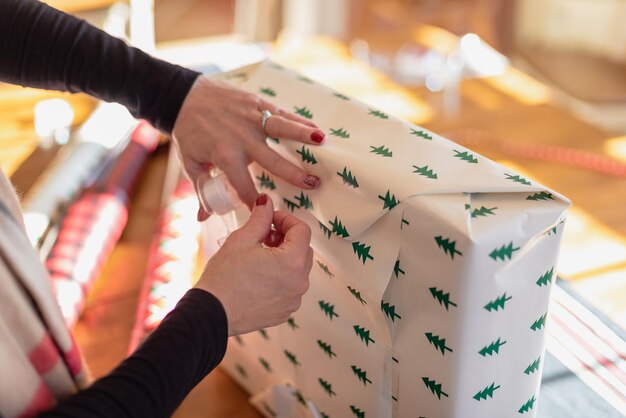 Foto mãos cortadas de mulher embrulhando pacote na mesa