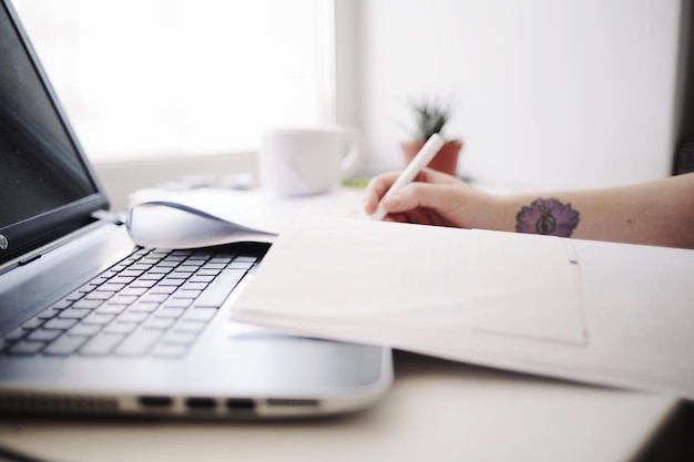 Mãos cortadas de mulher escrevendo em uma mesa no escritório