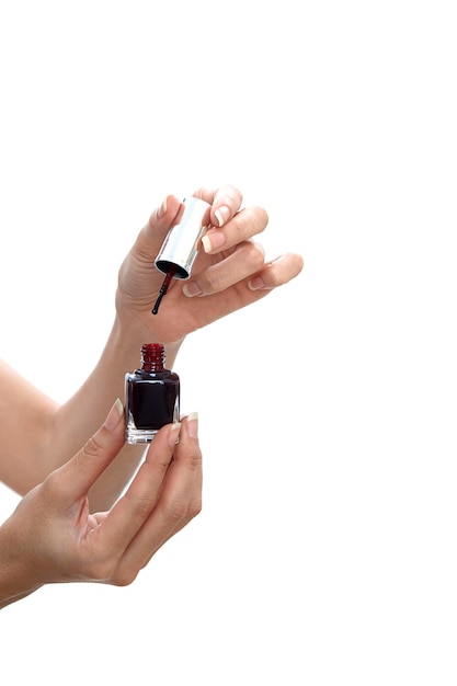 Mãos cortadas de mulher segurando uma garrafa de esmalte de unhas contra um fundo branco