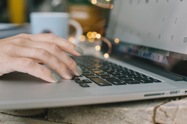 Mãos cortadas de mulher usando laptop na mesa em casa