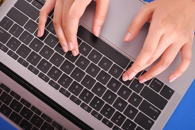 Mãos cortadas de mulher usando laptop na mesa
