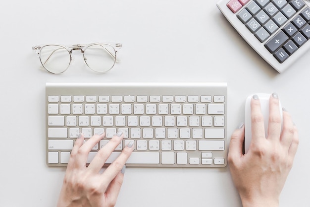 Foto mãos cortadas de mulher usando teclado e mouse de computador na mesa