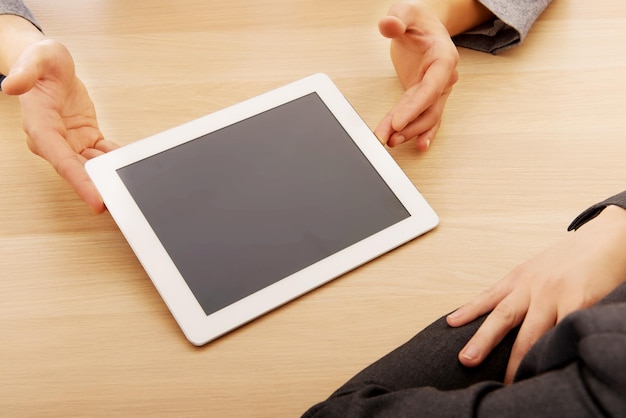Foto mãos cortadas de mulheres de negócios usando tablet digital na mesa