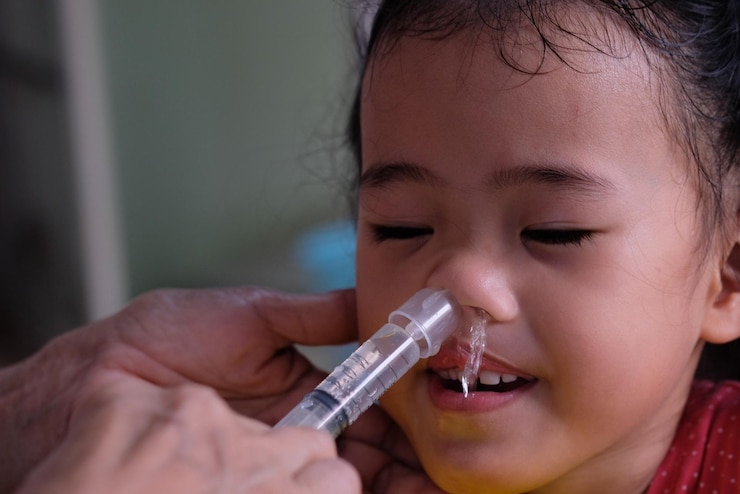 Foto mãos cortadas de pai injetando remédio no nariz da filha