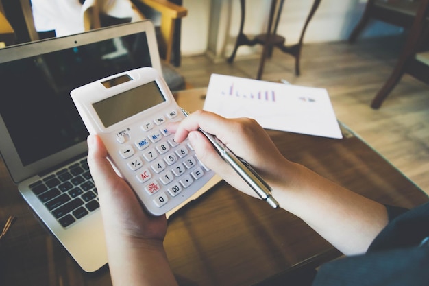 Foto mãos cortadas de pessoa usando calculadora sobre laptop na mesa