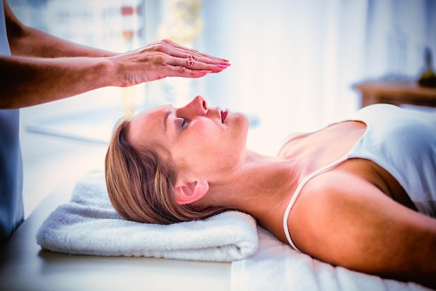 Mãos cortadas de terapeuta realizando reiki em mulher