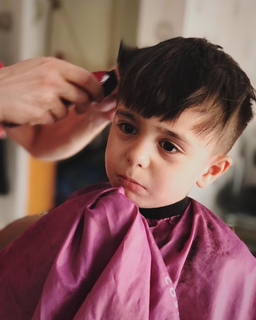 Mãos cortadas de um barbeiro a cortar o cabelo de um rapaz.