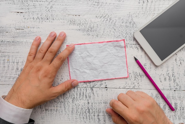 Mãos cortadas de um empresário segurando papel na mesa.