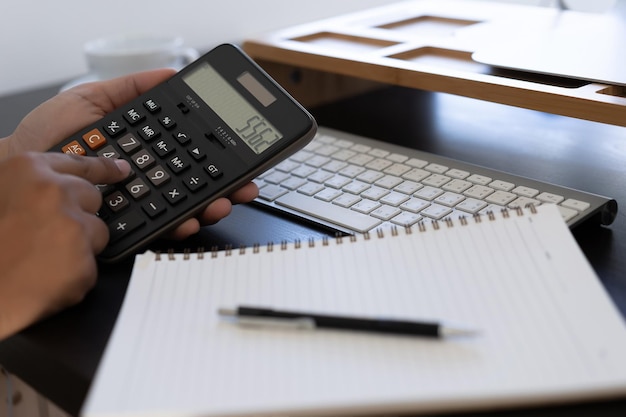 Mãos cortadas de um empresário usando uma calculadora sobre a mesa no escritório