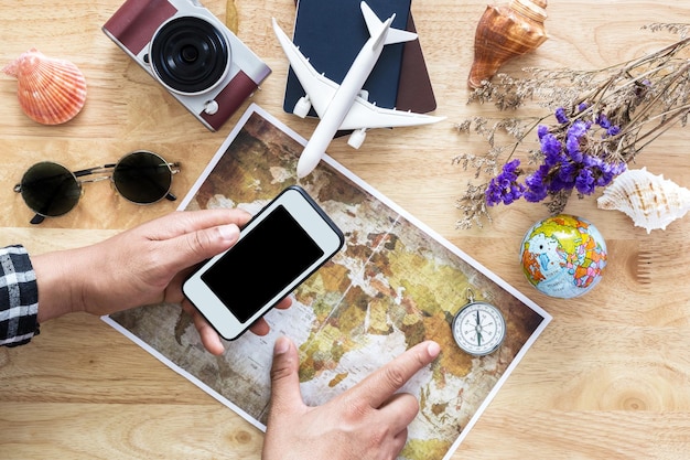 Foto mãos cortadas de um homem segurando um telefone móvel sobre um mapa na mesa