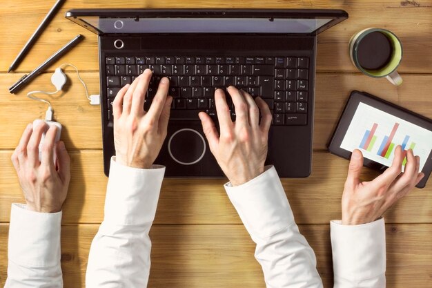 Foto mãos cortadas de um homem usando tablet digital e laptop no escritório