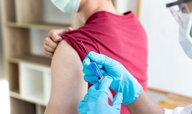 Foto mãos cortadas de um médico injetando uma seringa em um homem no hospital