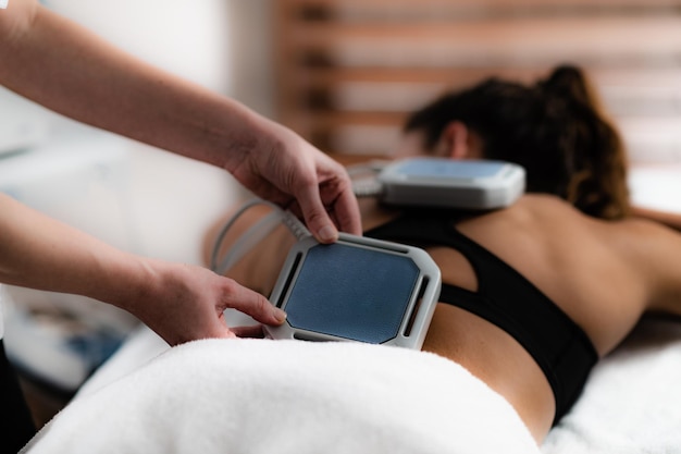 Foto mãos cortadas de uma massagista a massagear uma cliente feminina num spa.