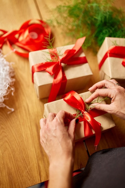 Mãos cortadas de uma mulher irreconhecível embalando um presente de Natal