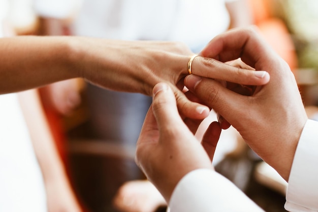 Foto mãos cortadas do noivo usando anel de casamento para a noiva