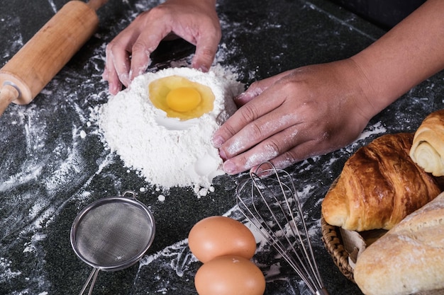 Mãos cortadas preparando comida na mesa.