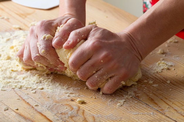 Mãos cortadas preparando massa de macarrão na mesa